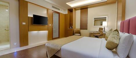 Una habitación de hotel con una cama grande, un escritorio, una silla, un televisor y una puerta corredera.