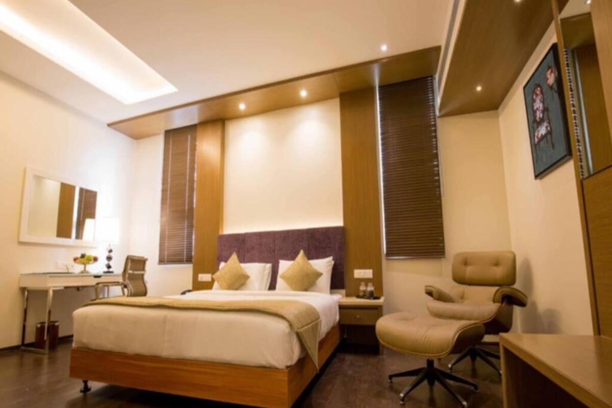 A hotel room with a bed, a desk, a chair, and a nightstand.