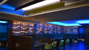A modern lounge area with a seating arrangement and a decorative wall with illuminated panels. - Hotel Kiscol Grands (Coimbatore)