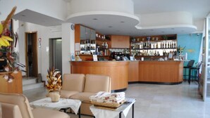 A hotel lobby with a bar area, seating, and a reception desk. - Hotel Nancy (Rimini)