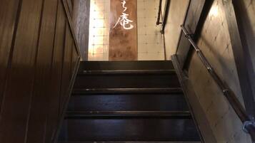 Una escalera de madera con barandillas metálicas y un panel de madera con caracteres japoneses.