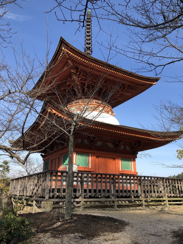 Een traditionele Japanse pagode met een meerlaagse dakconstructie, omringd door een houten hek en bomen.