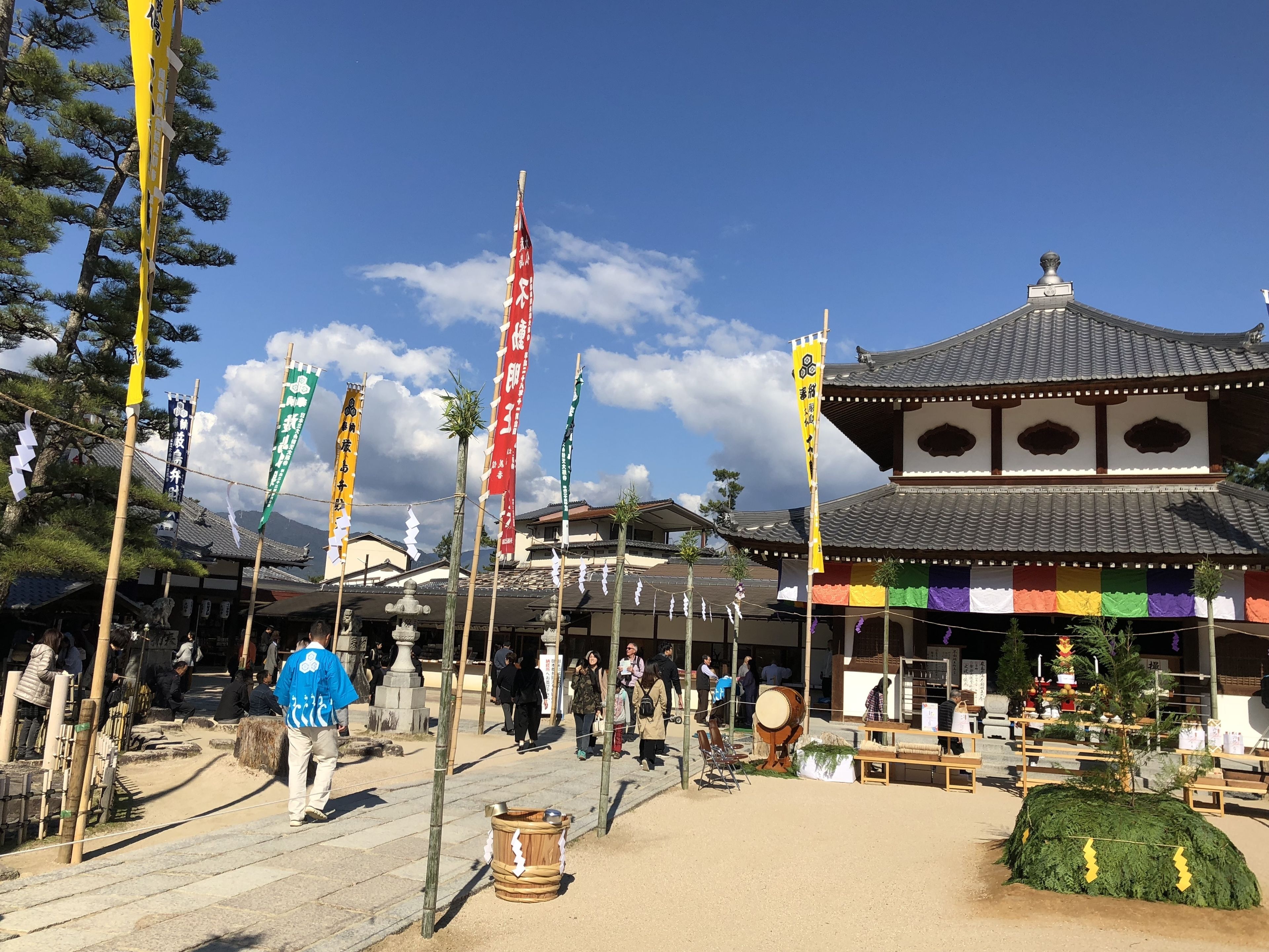 A traditional Japanese building with a tiled roof and multiple flags.