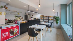 A modern cafe with a counter, seating area, and shelves with snacks. - JR Mansion (Bangkok)