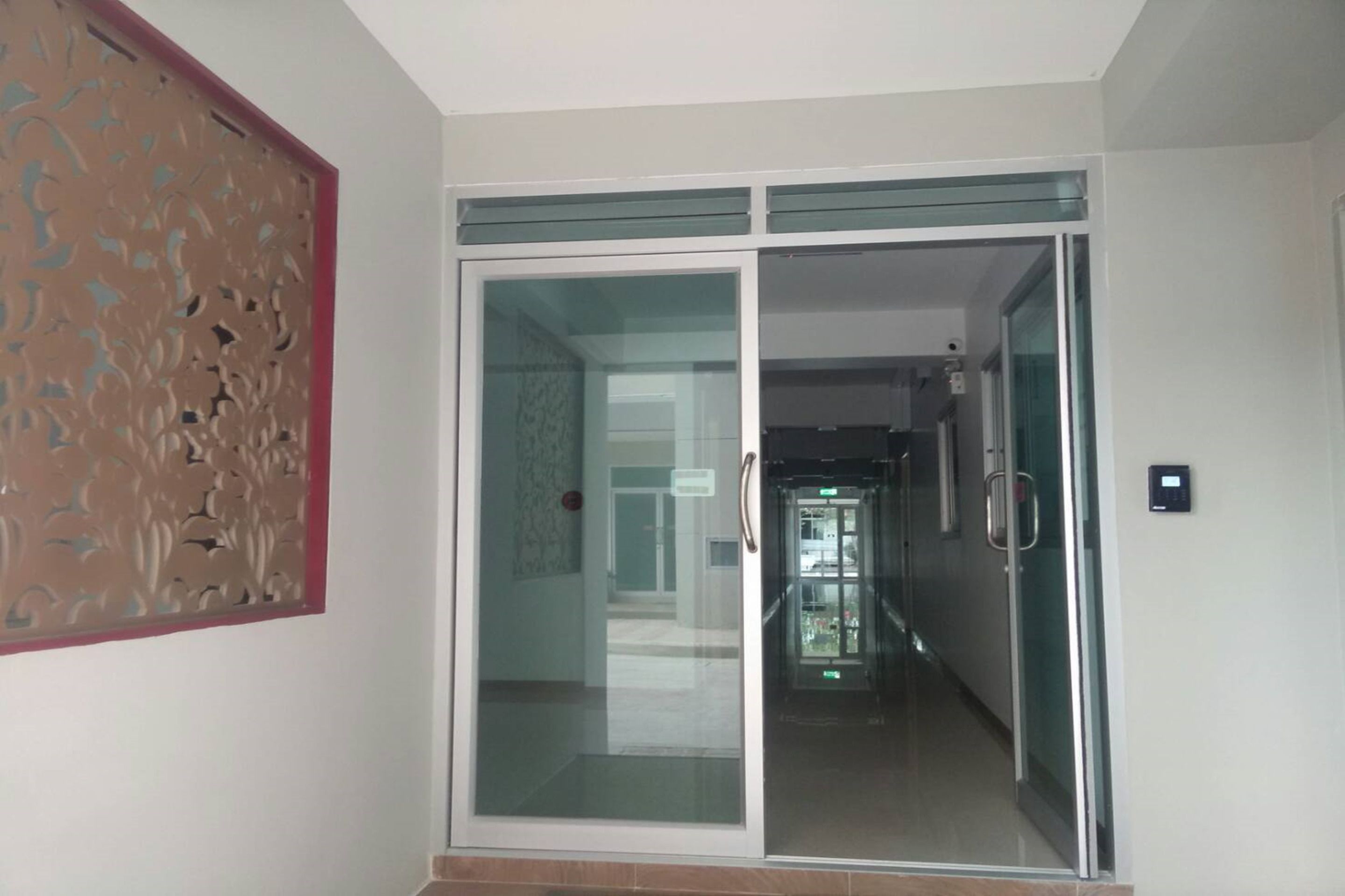A hallway with a glass door leading to a corridor.
