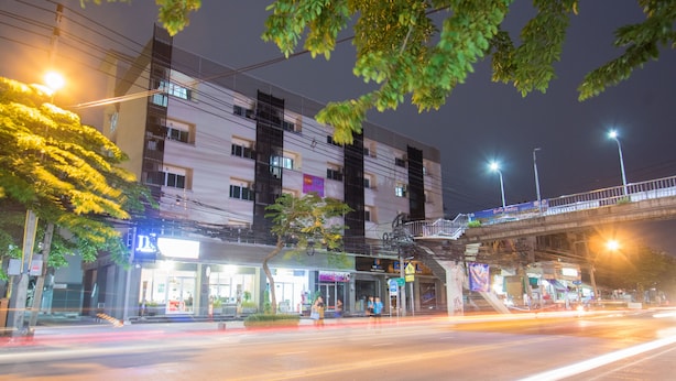 A multi-story building with a ground-level commercial area, including a brightly lit storefront. - JR Mansion (Bangkok)