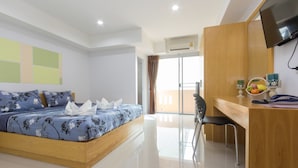 A modern hotel room with a wooden bed, a desk with a chair, a flat-screen TV, and a balcony with a view. - JR Mansion (Bangkok)