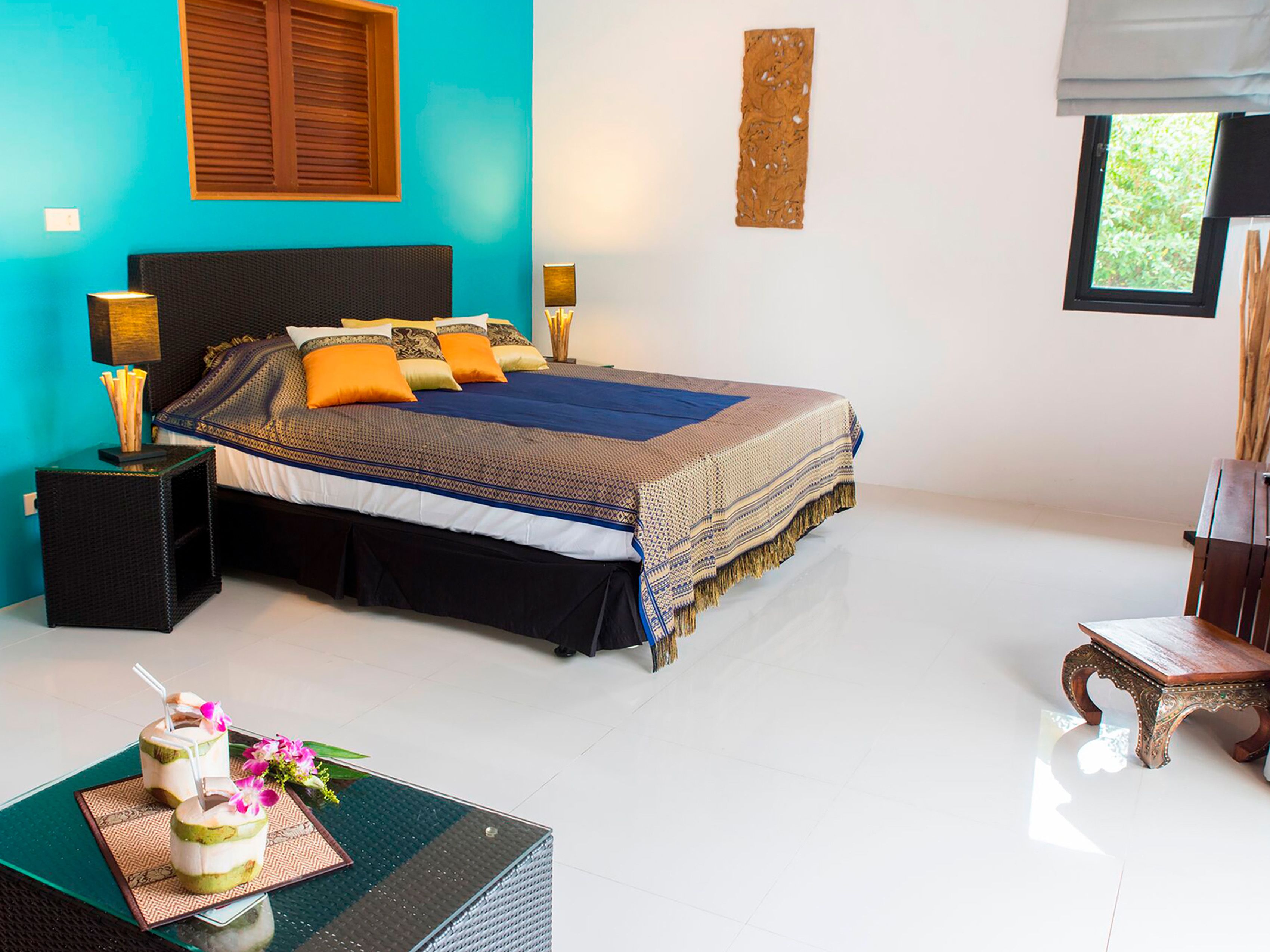 Une chambre à coucher avec un lit, des tables de chevet, une table avec des boissons et une chaise.
