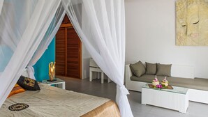 Een slaapkamer met een bed, nachtkastje, slaapbank, salontafel en een schilderij aan de muur.
