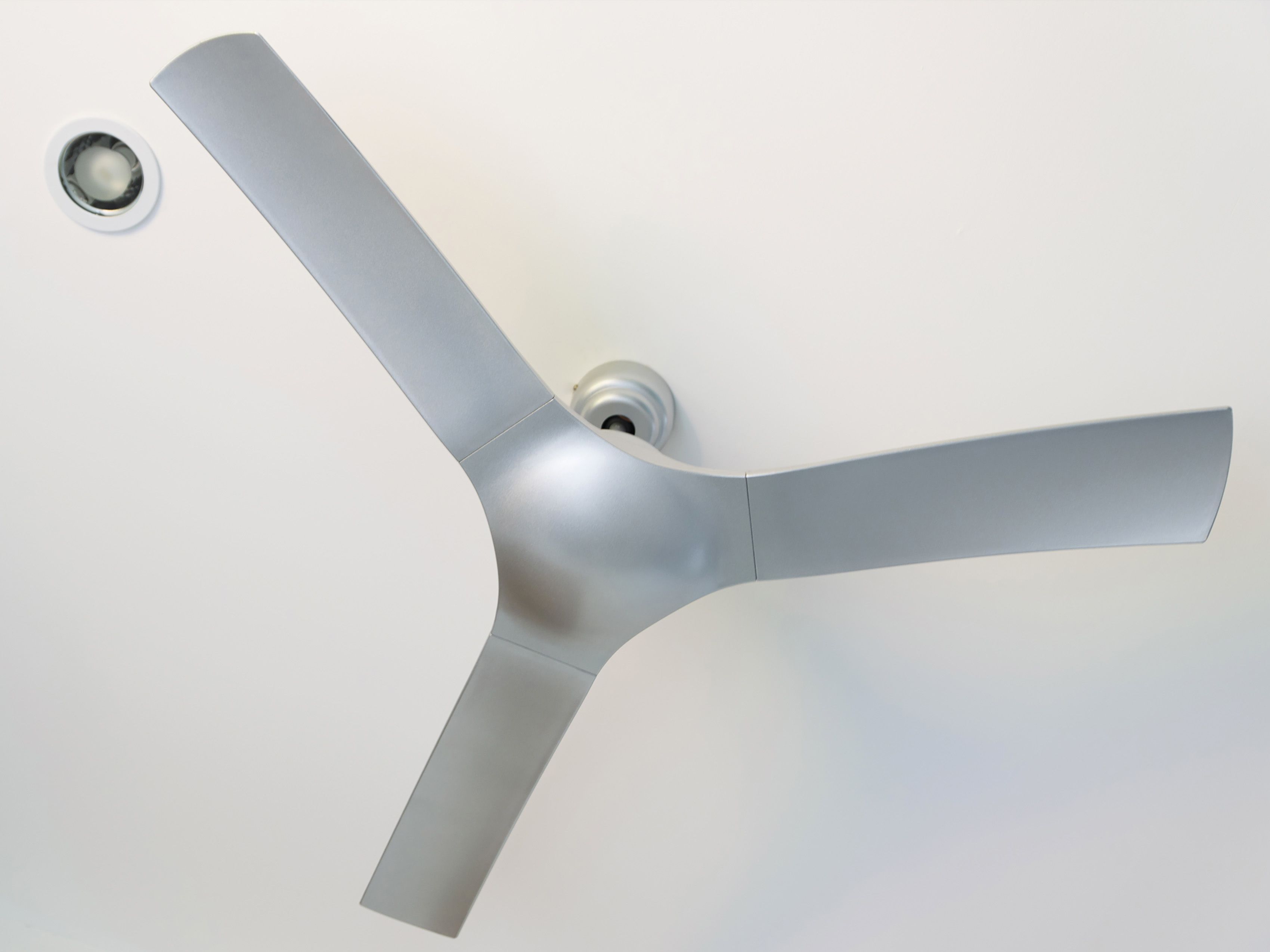 Un ventilador de techo con tres aspas instalado en un techo blanco.