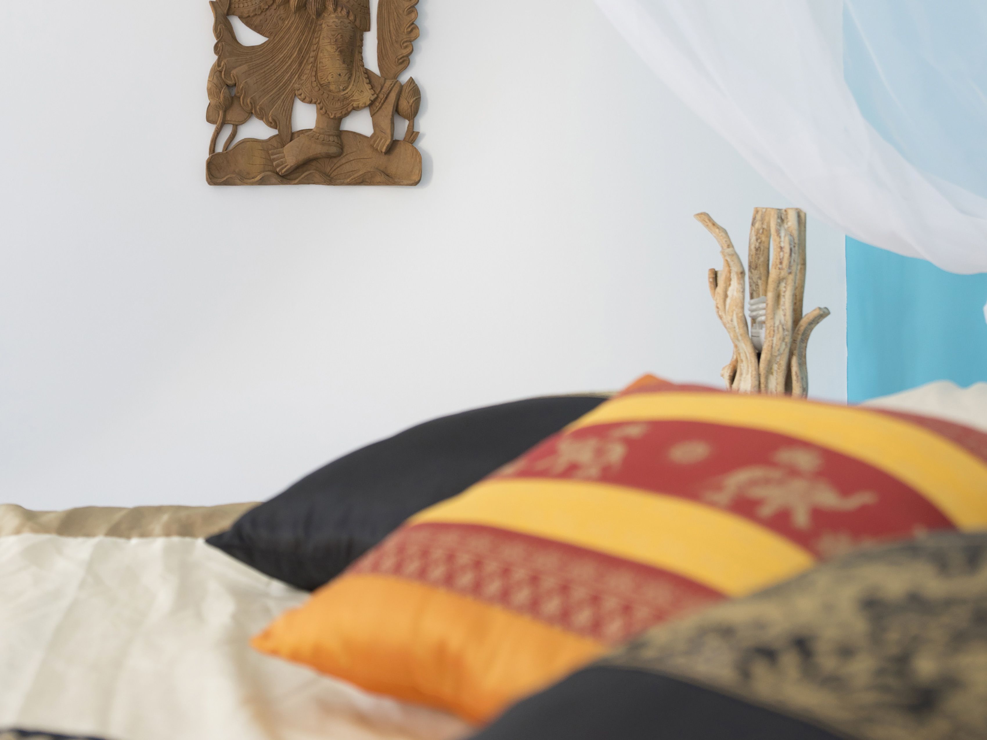 Una cama con muchos cojines y un adorno en la pared.