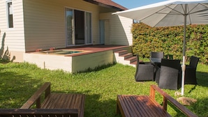 Een huis met een zwembad, tuinmeubilair en een grote parasol.