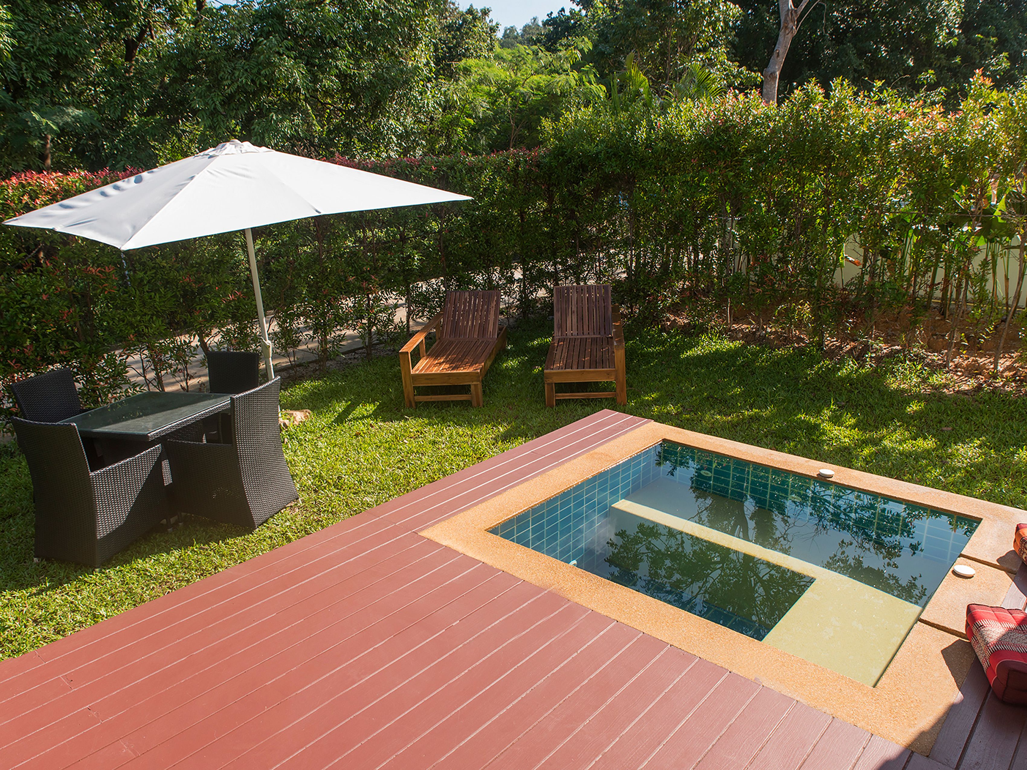 A backyard with a pool, a dining table, and two chairs.