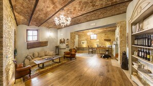 A spacious living room with a high ceiling, stone walls, a wooden floor, a sofa, a coffee table, and a dog lying on the floor. - Agriturismo Il Segreto di Pietrafitta (San Gimignano)