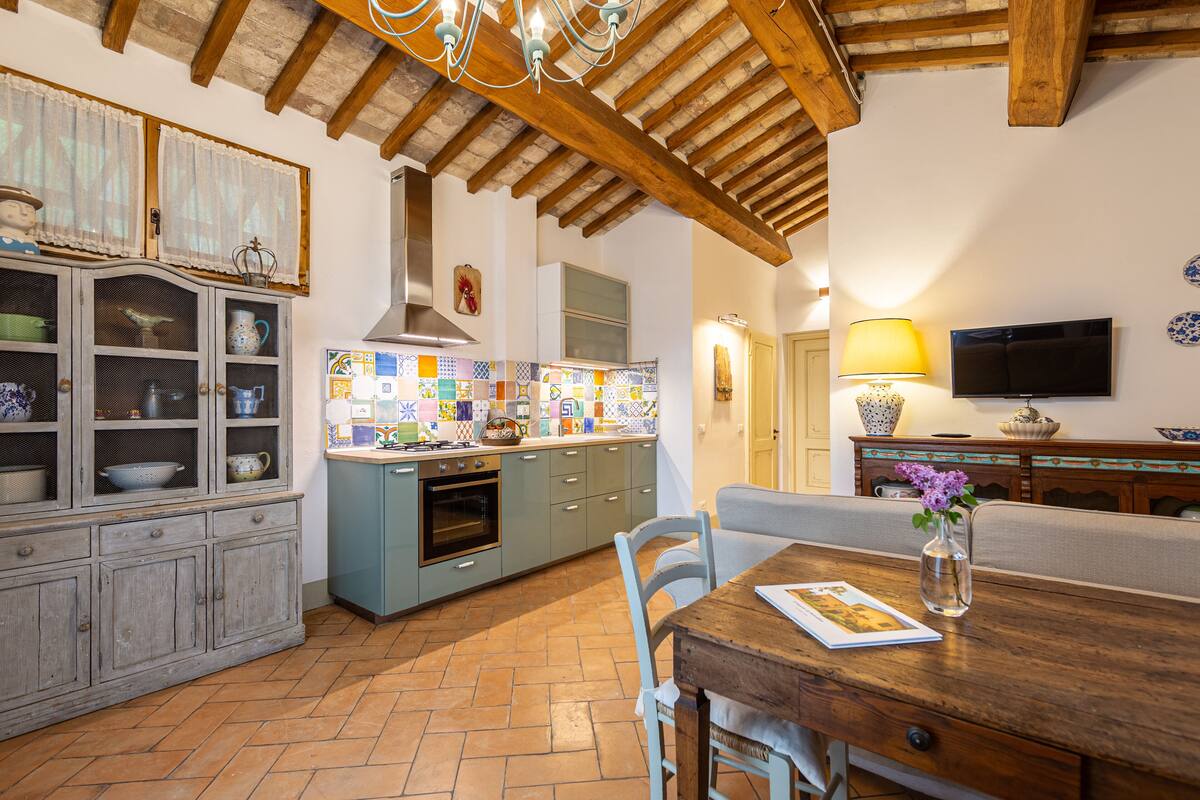 Una cocina con salpicadero de azulejos, armarios de madera y un comedor con mesa y sillas.