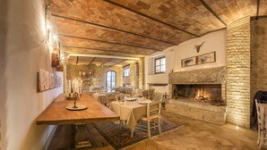 A rustic dining area with a stone fireplace, wooden beams, and a long table set for dining. - Agriturismo Il Segreto di Pietrafitta (San Gimignano)