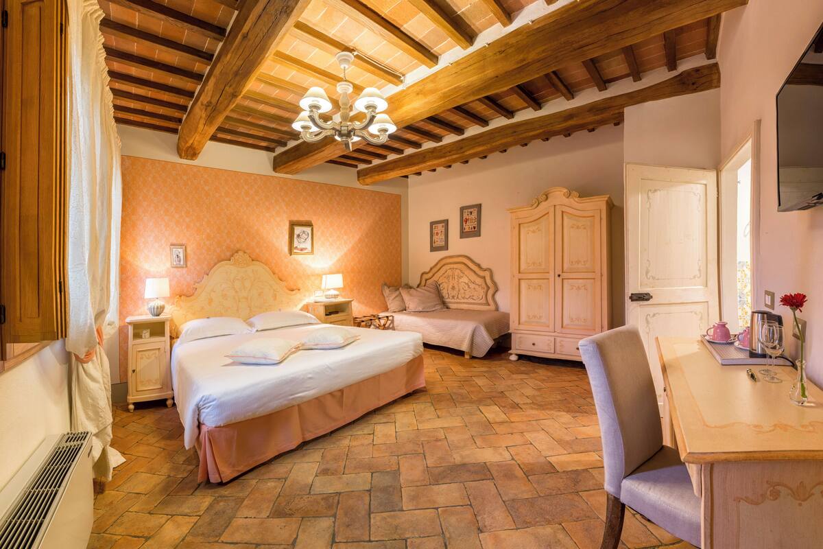 Un dormitorio con una cama grande, una silla, una mesa y un armario.