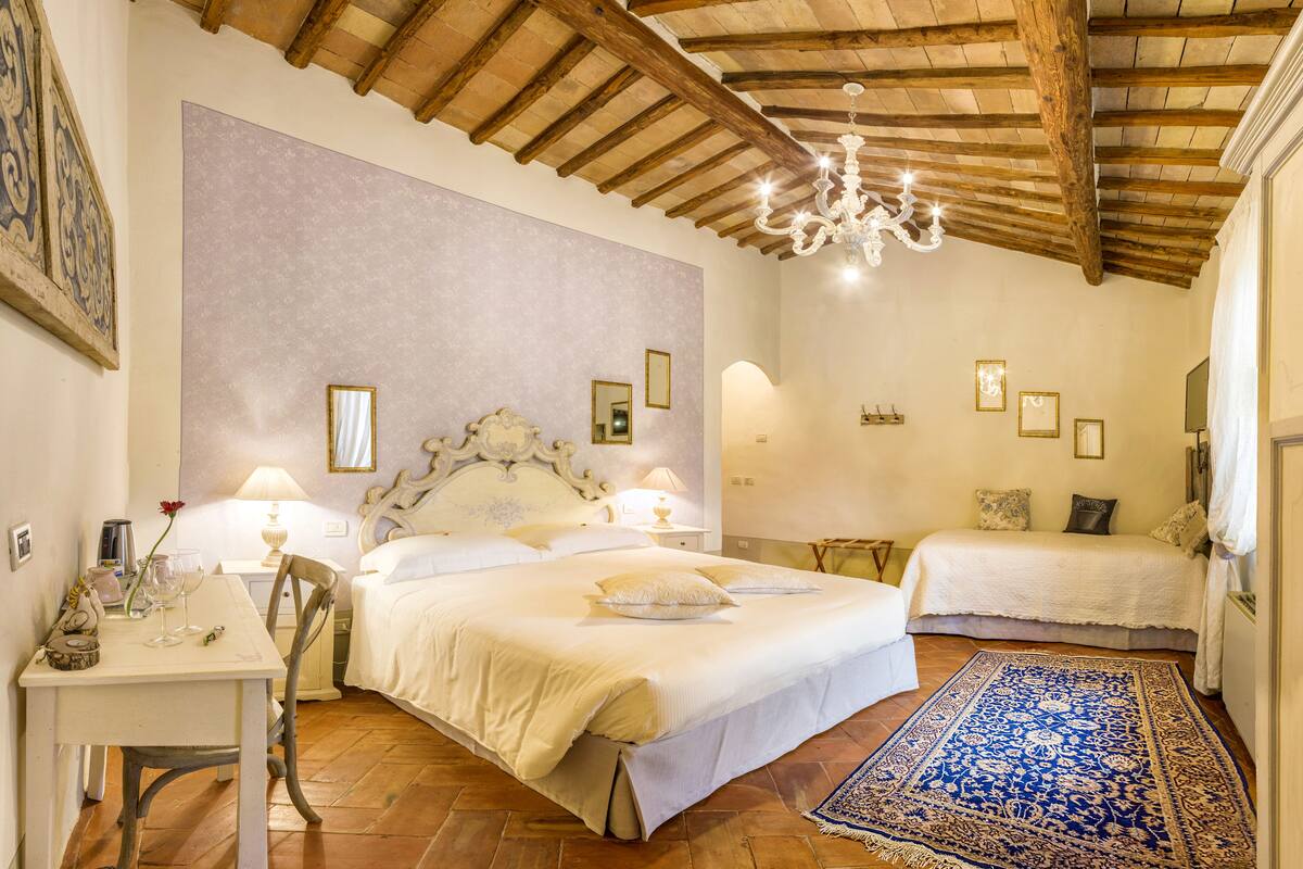 Un dormitorio con una cama grande, una cama más pequeña, un escritorio con una silla y una araña.