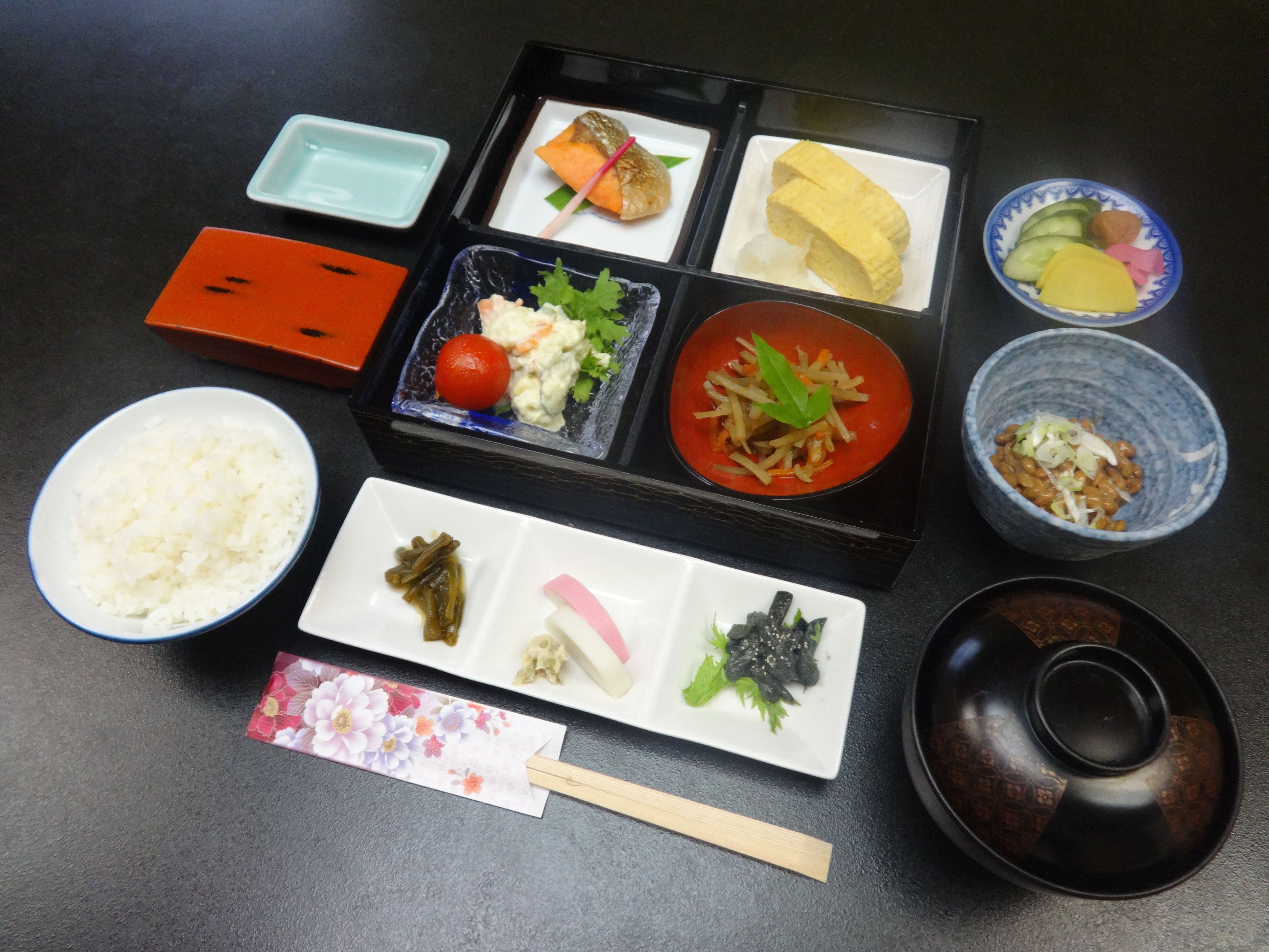 A meal set with various dishes including rice, vegetables, and a bowl of soup.