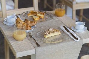 A breakfast table with croissants, a slice of cake, a glass of orange juice, and a cup of coffee. - Les Suites Magnolia (Olbia)