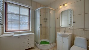 A modern bathroom with a shower, sink, toilet, and a window with blinds. - Apartament Krupowki 73 - 7 Person (Zakopane)