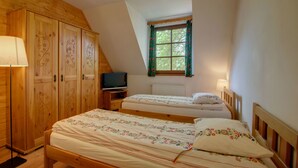 A bedroom with two beds, a wooden wardrobe, a television, and a window with curtains. - Apartament Krupowki 73 - 7 Person (Zakopane)
