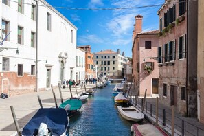 A narrow canal with boats docked on both sides, flanked by historic buildings with balconies and shutters. - InLaguna (Venice)
