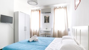 A hotel room with a bed, a desk, a chair, and a TV mounted on the wall. - InLaguna (Venice)