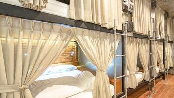 A hotel room with bunk beds, each with a curtain. There are numbers on the wall indicating room numbers.