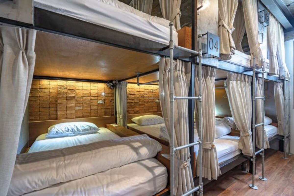 A bunk bed room with curtains, a stone wall, and a number sign.