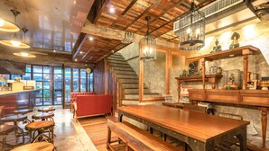 Un intérieur rustique avec un bar en bois, de hauts plafonds et un escalier.