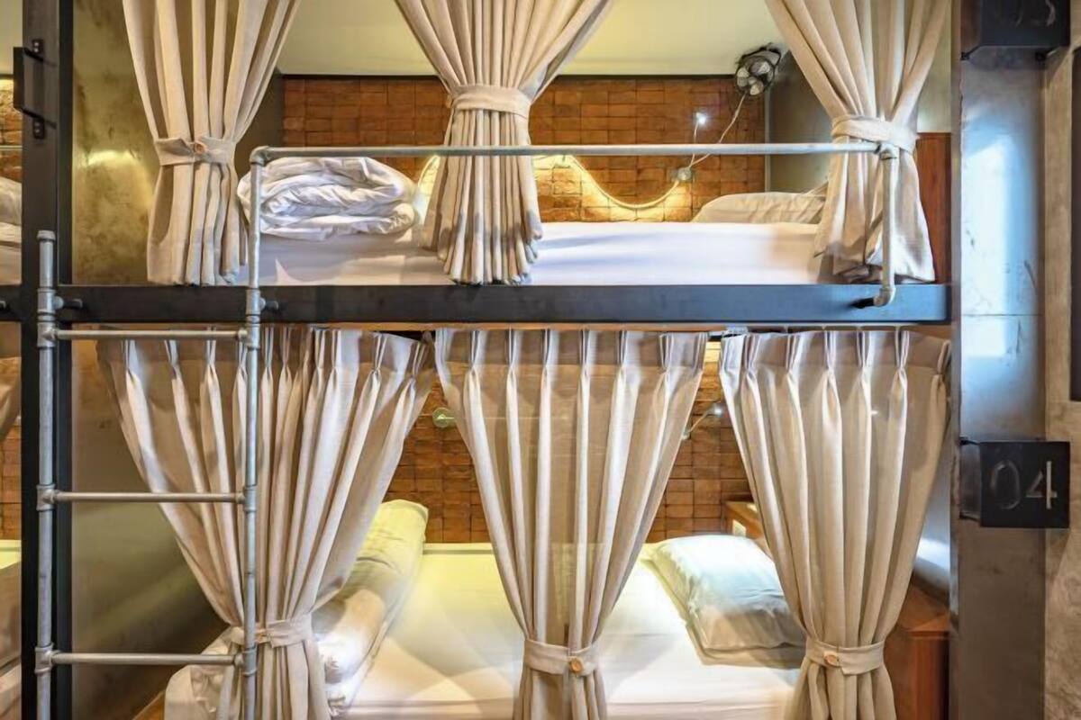 A bunk bed room with curtains, a brick wall, and a number sign.