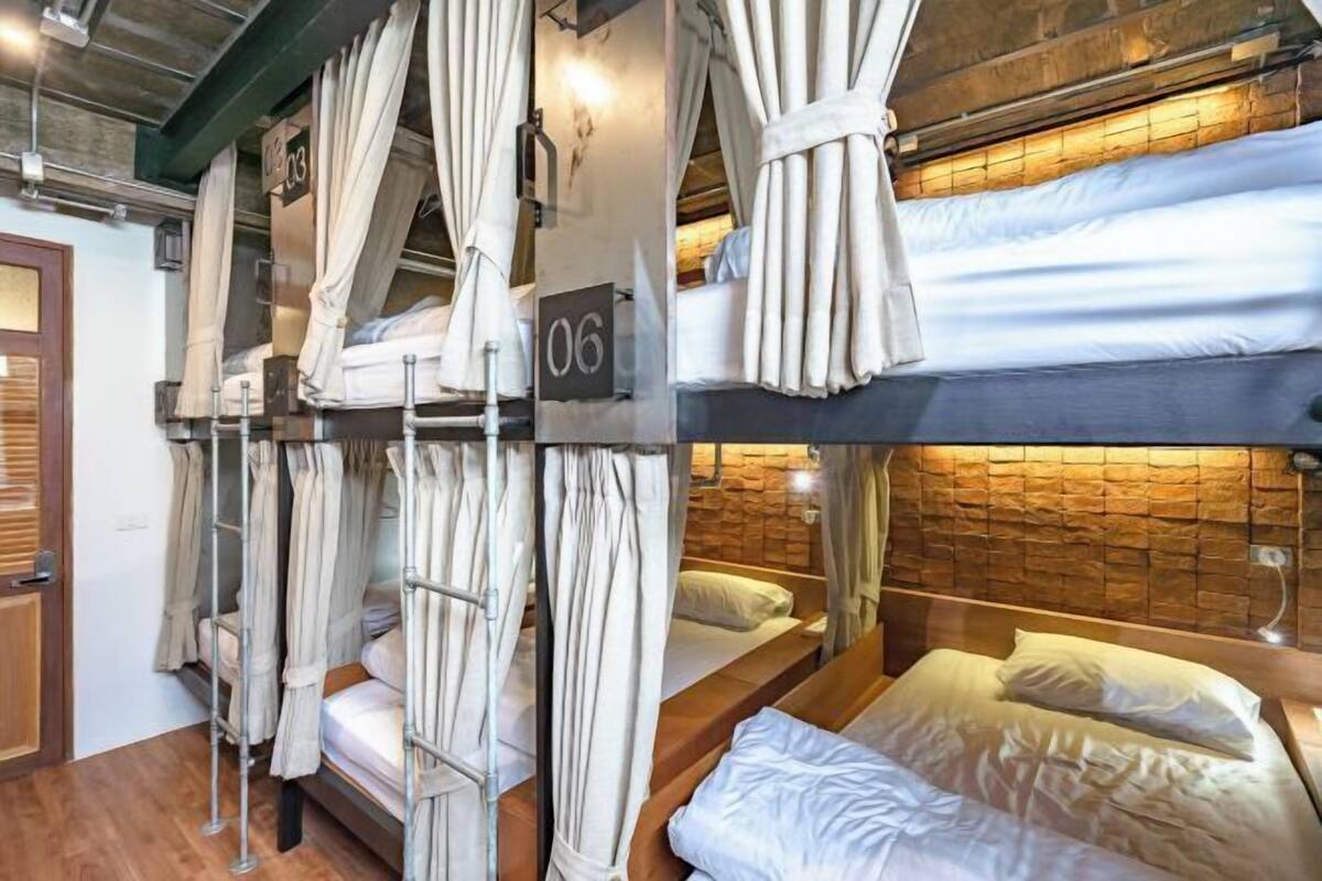 A room with bunk beds, curtains, a stone wall, and a wooden door.