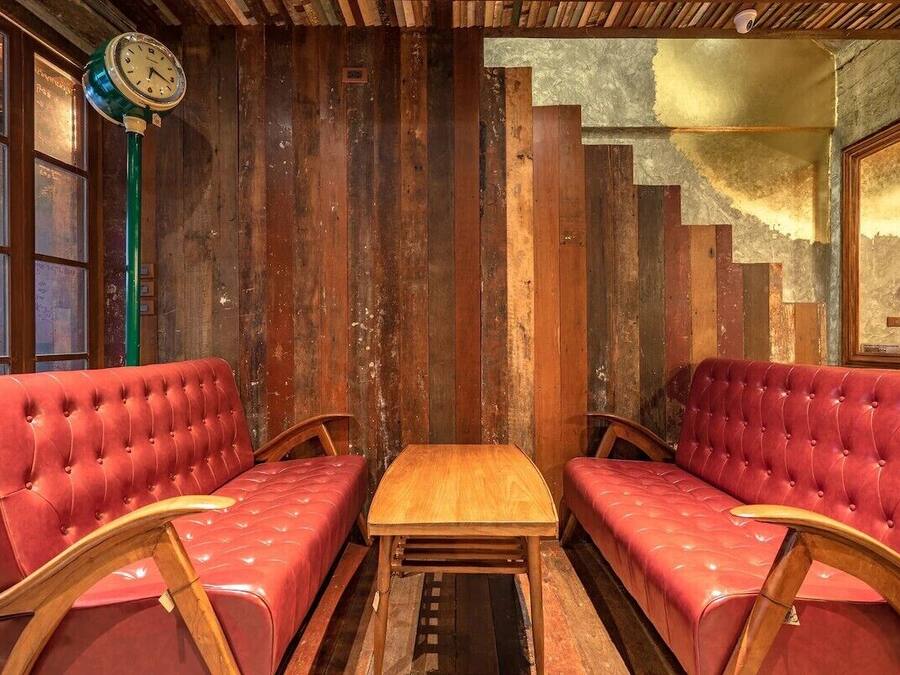 Una habitación con dos sofás de cuero rojo, una mesa de madera y un reloj sobre un poste verde.