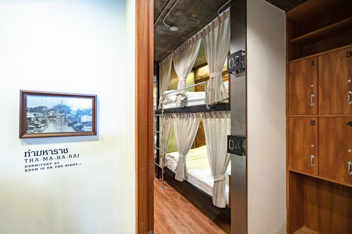 A dormitory room with bunk beds, wooden cabinets, and a framed picture on the wall.