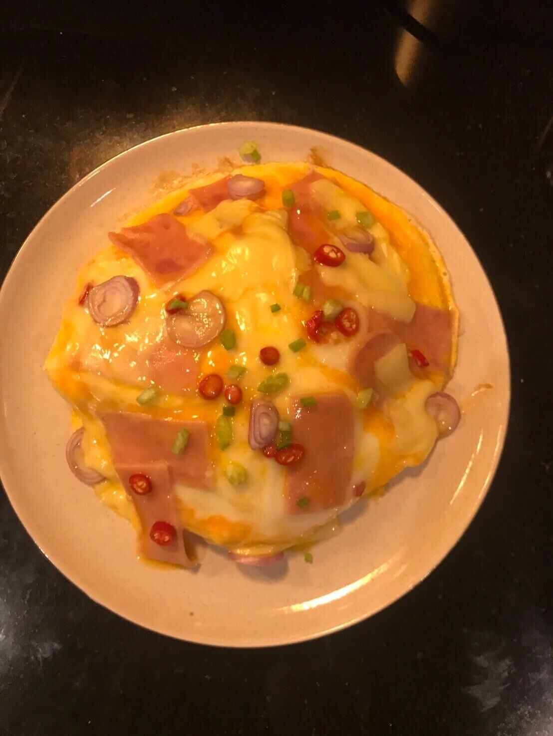 A plate of food with cheese, ham, and green onions.