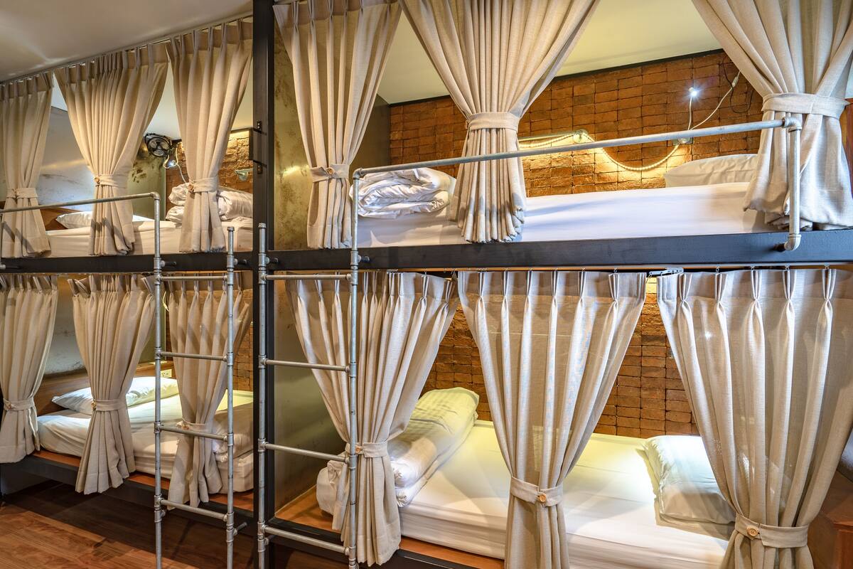A hotel room with bunk beds, each with a curtain.