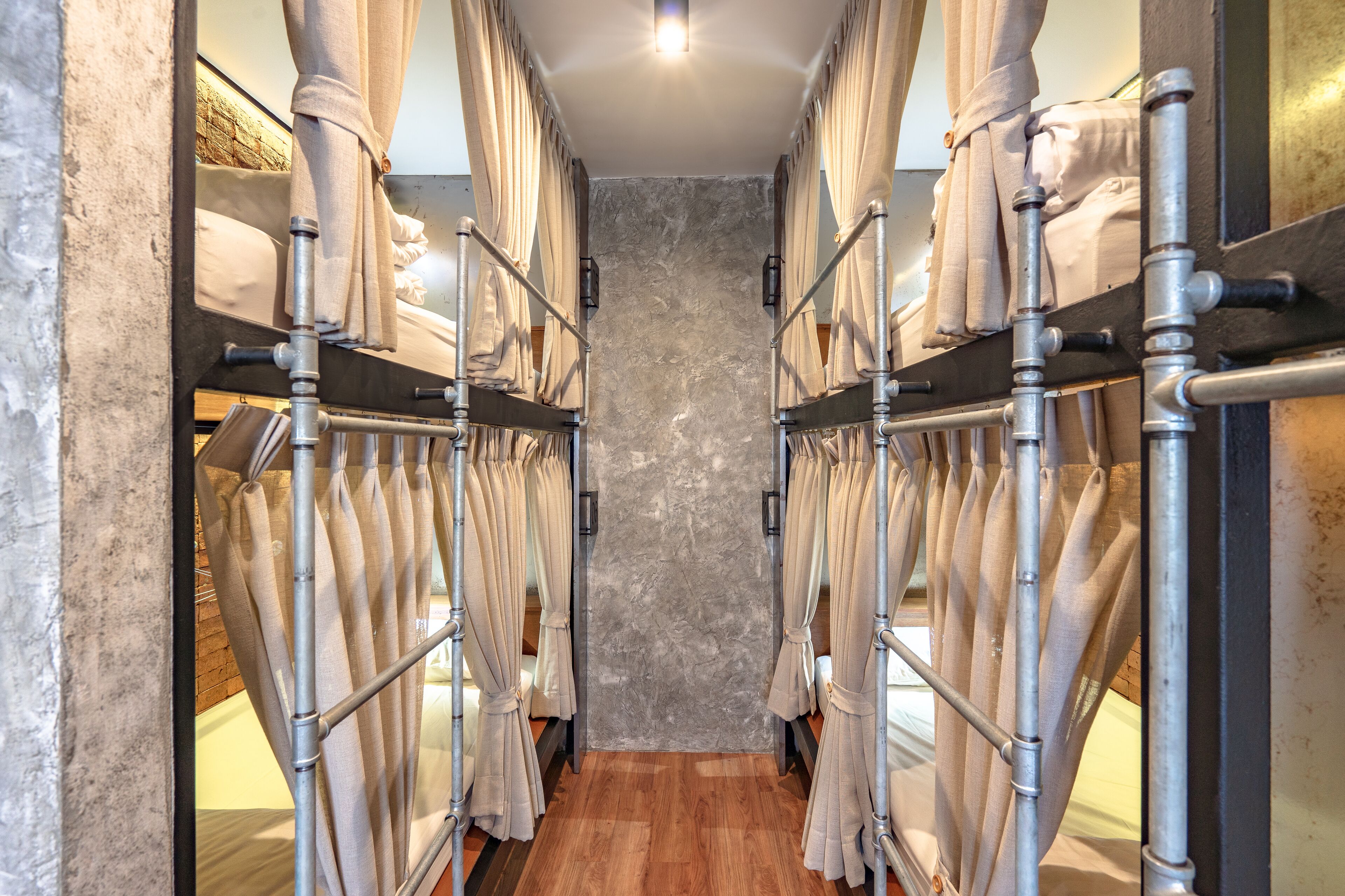 A corridor with multiple beds, each with a curtain and metal frame.