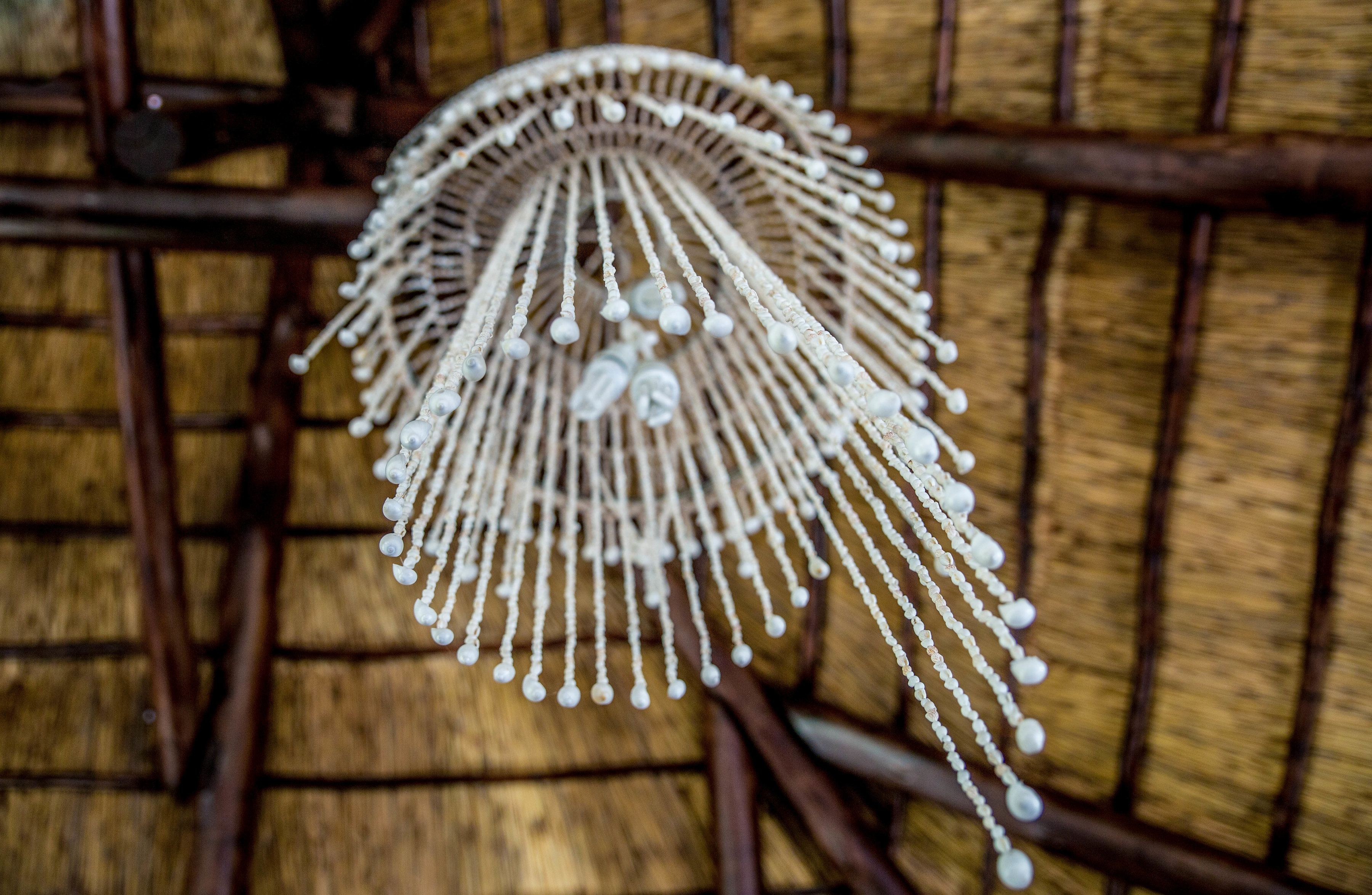 A decorative item with multiple strands and spherical elements, hanging against a wooden background.