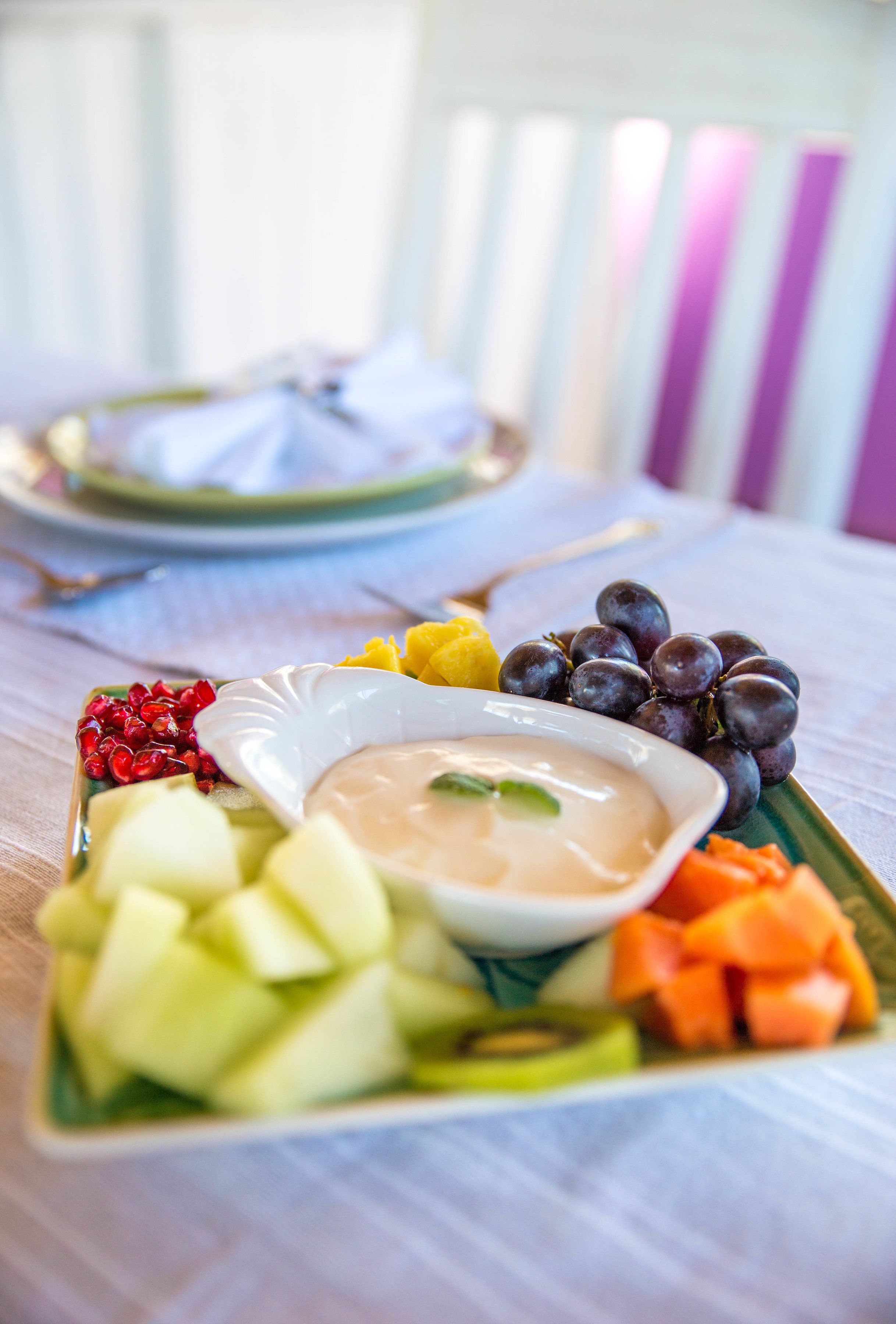 A table with a fruit platter and a bowl of dip.