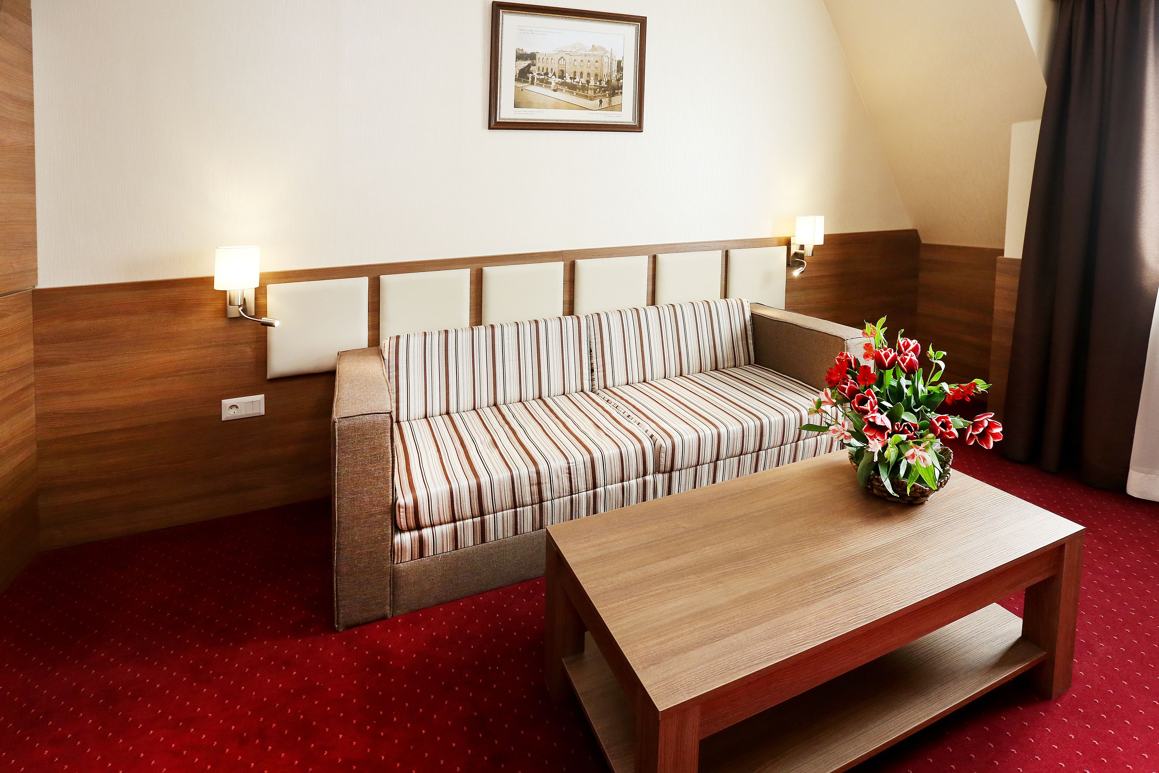 A hotel room with a striped sofa, a wooden coffee table, and a framed picture on the wall.