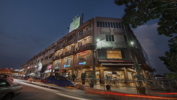 Een hotel met meerdere verdiepingen, balkons, een zichtbaar restaurantbord en terrasplekken.