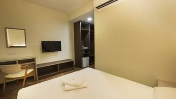 A hotel room with a bed, a desk with a chair, a television, and a wardrobe.
