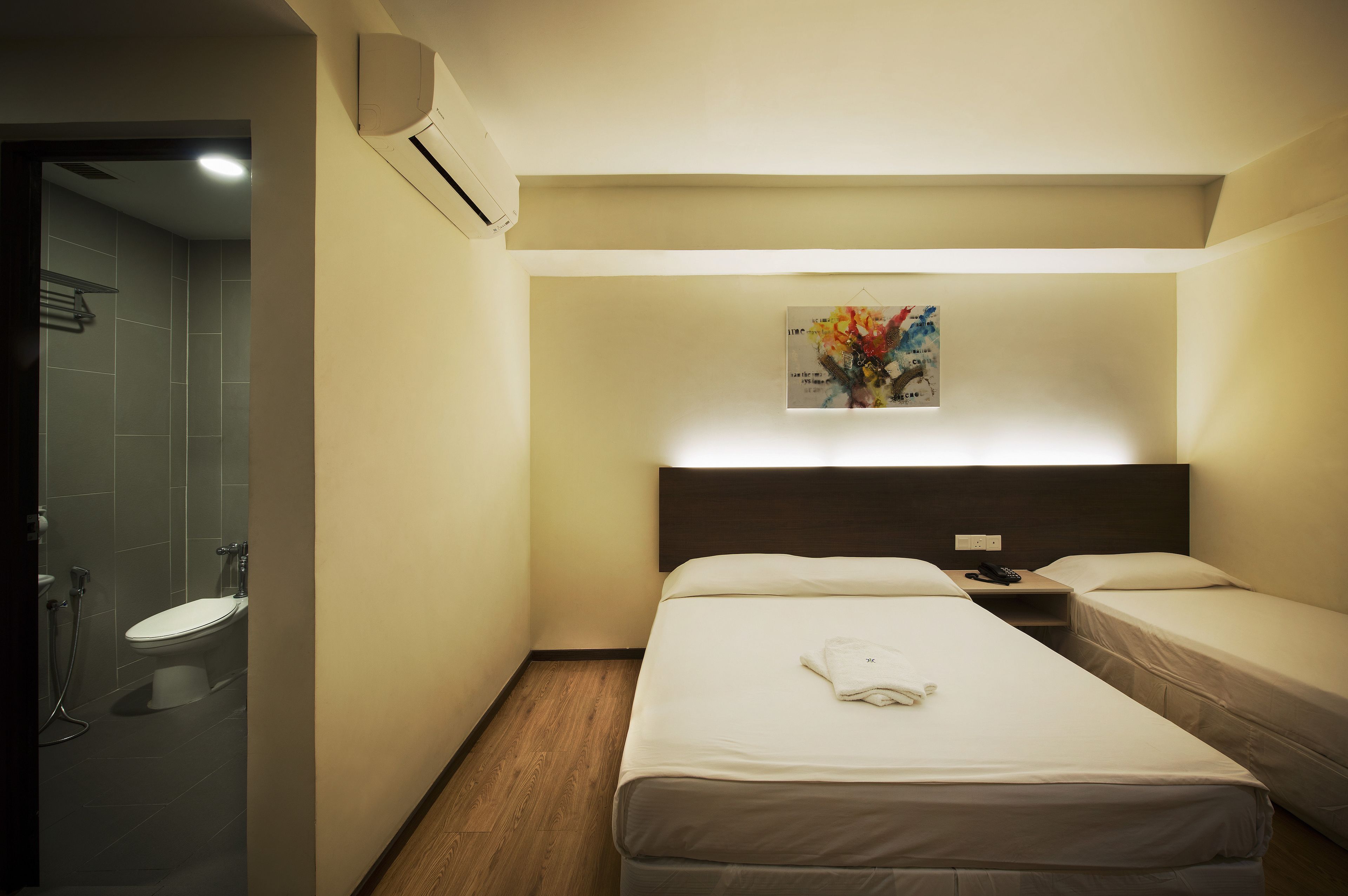 Habitación de hotel con dos camas individuales, ducha e inodoro.