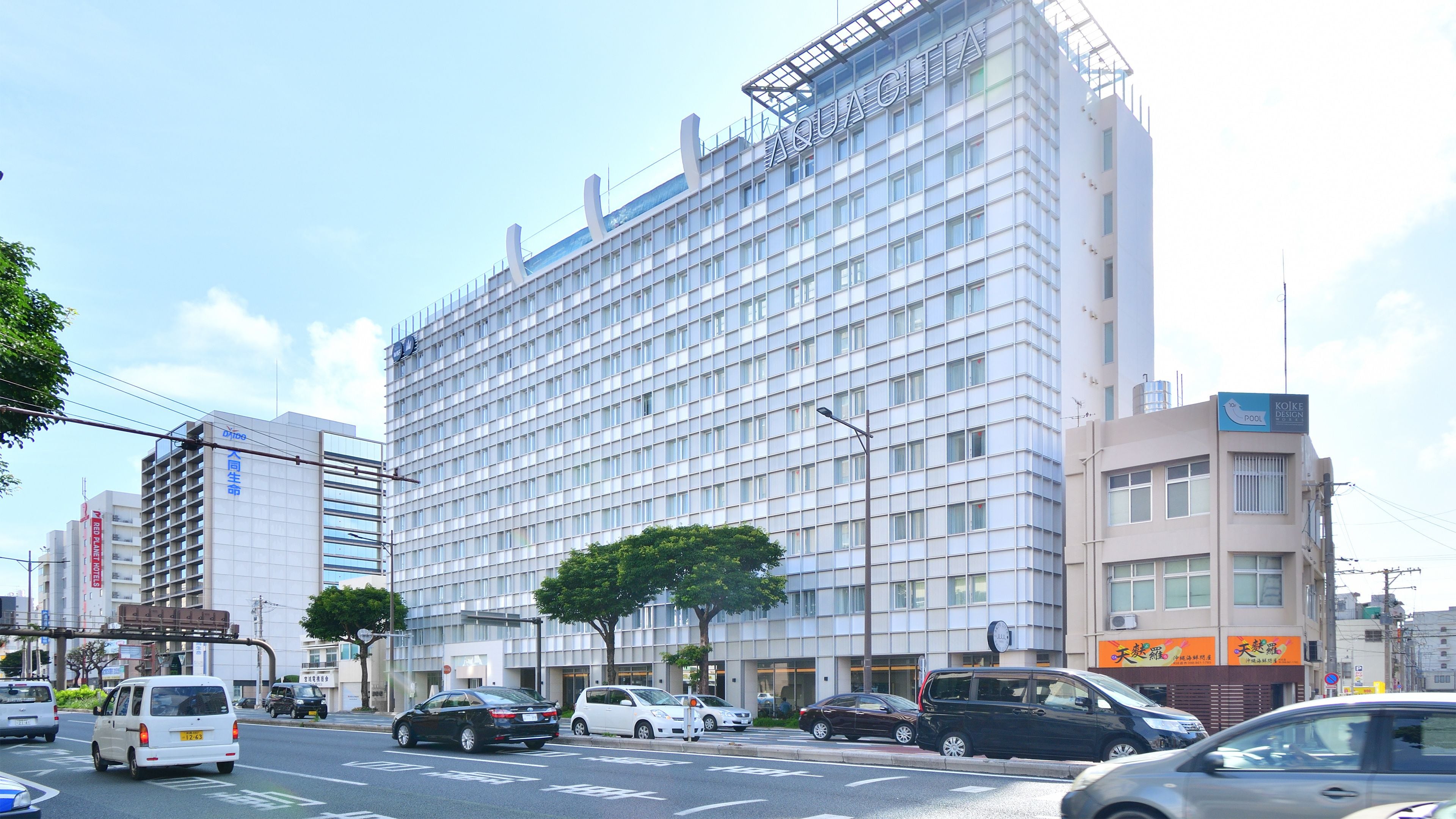 Un moderno edificio de hotel con fachada tipo entramado, varios pisos y un letrero llamativo en la parte superior.