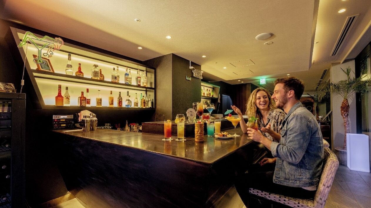 Un espace bar avec un comptoir, différentes bouteilles et des verres.