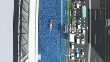 A person in a swimming pool with a view of parked cars and a building.