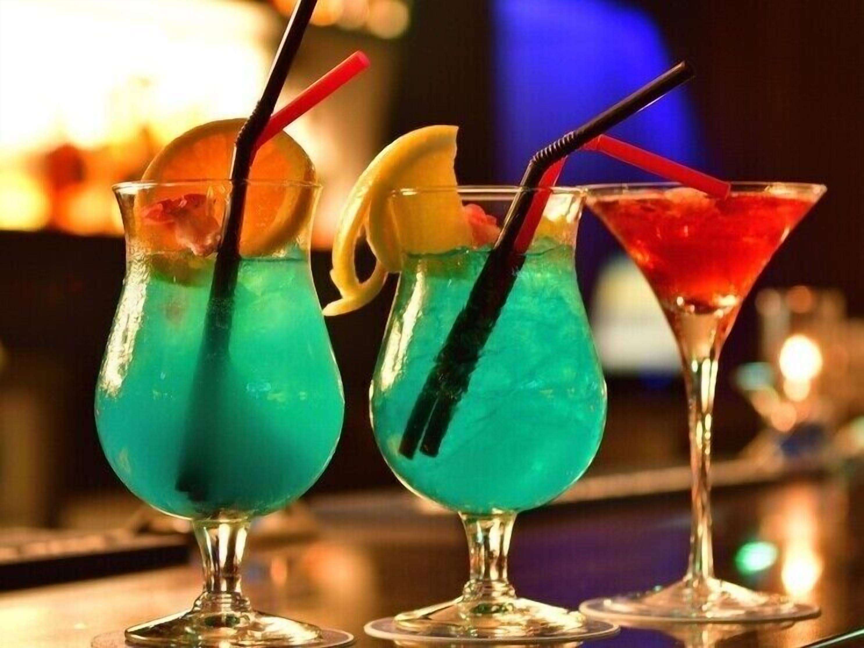 Trois cocktails servis dans des verres, avec des pailles et des décorations.