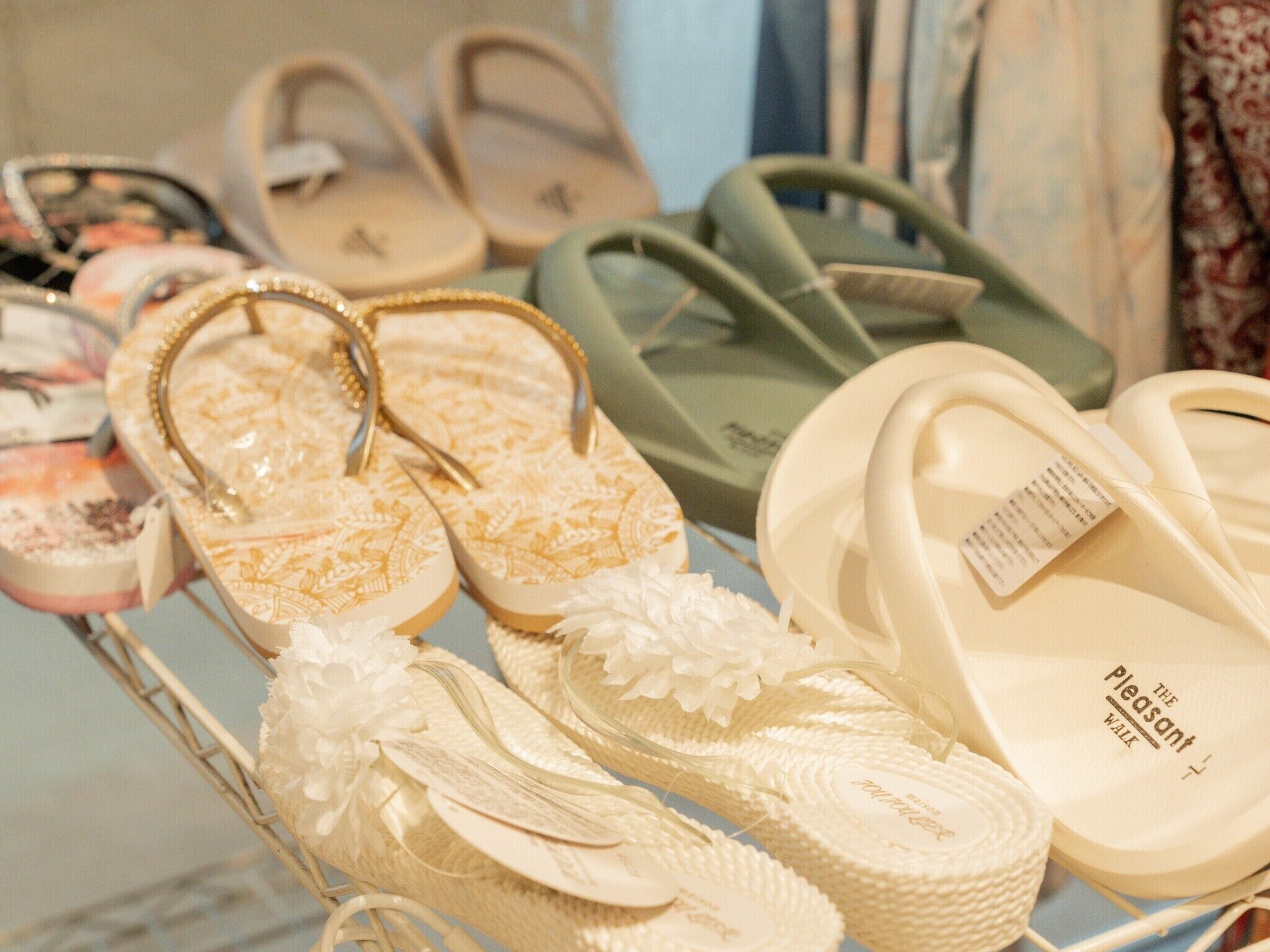 A variety of sandals displayed on a rack, including designs with floral patterns and different strap styles.