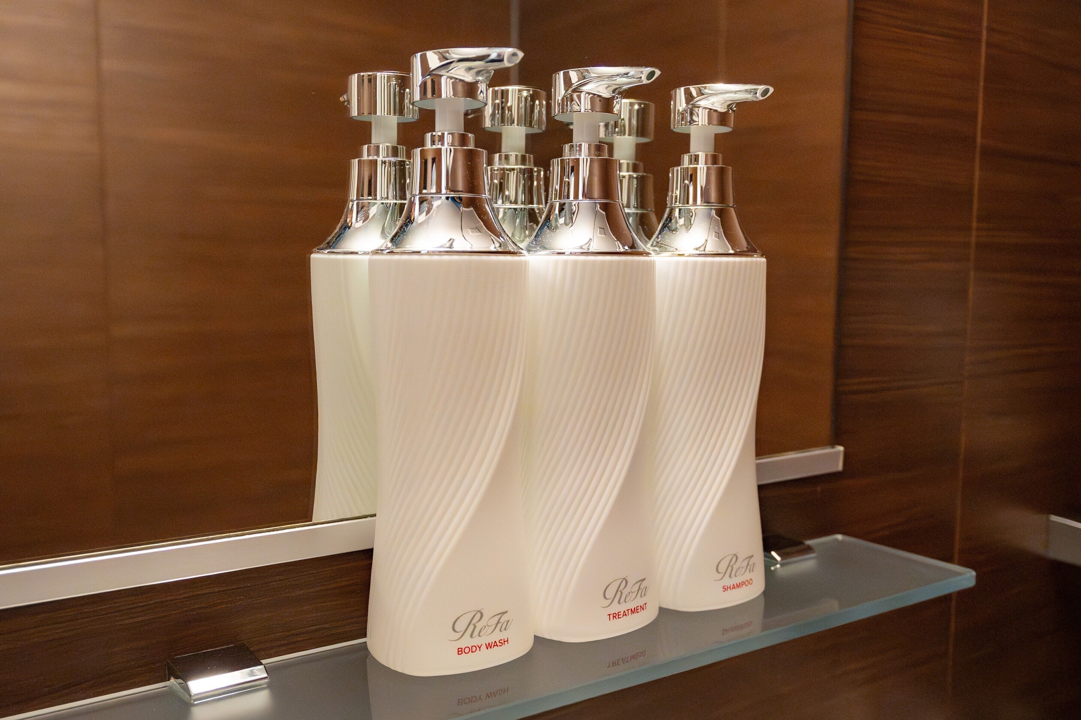 Un baño con espejo, paneles de madera y repisas con varias botellas de producto Re-Ta.
